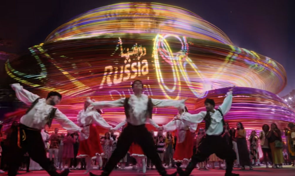 Three Russian Dancers in front of a crowd with a sign saying Russian Dubai Expo 2020